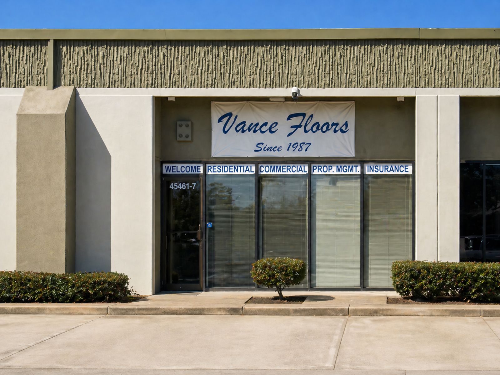 Vance Floors storefront on Fremont Boulevard, with the hand-painted ‘Vance Floors — Since 1987’ sign above the entrance and window panels labeled Welcome, Residential, Commercial, Prop. Mgmt., and Insurance.